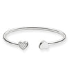 Silver cuff bracelet featuring two heart charms; one embellished with cubic zirconia.