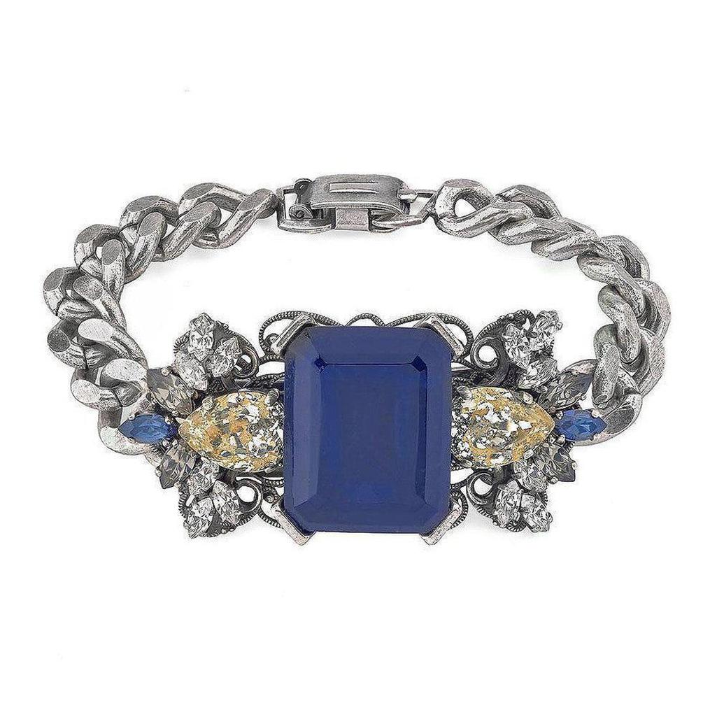 Geometric Crystal Cluster Bracelet: Silver chain bracelet featuring a large blue gemstone, accented with clear and yellow crystals.