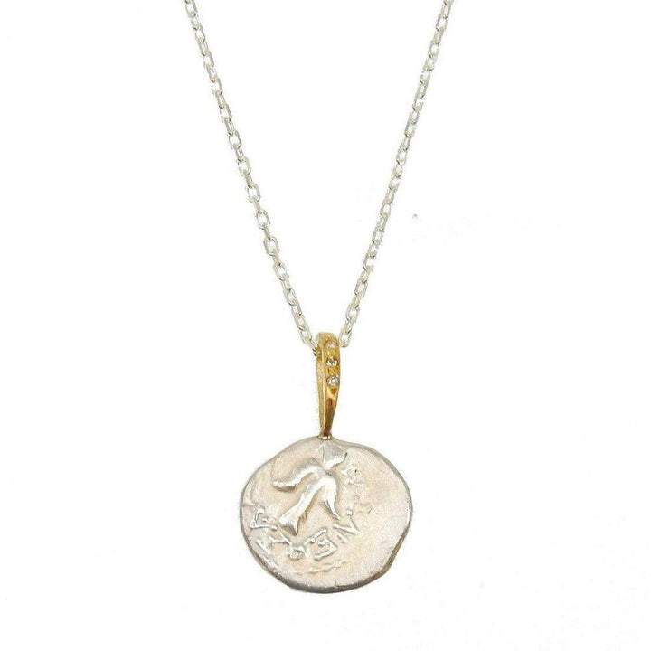Angel in Flight necklace: silver coin pendant with engraved bird, gold accents & diamonds, delicate chain.

