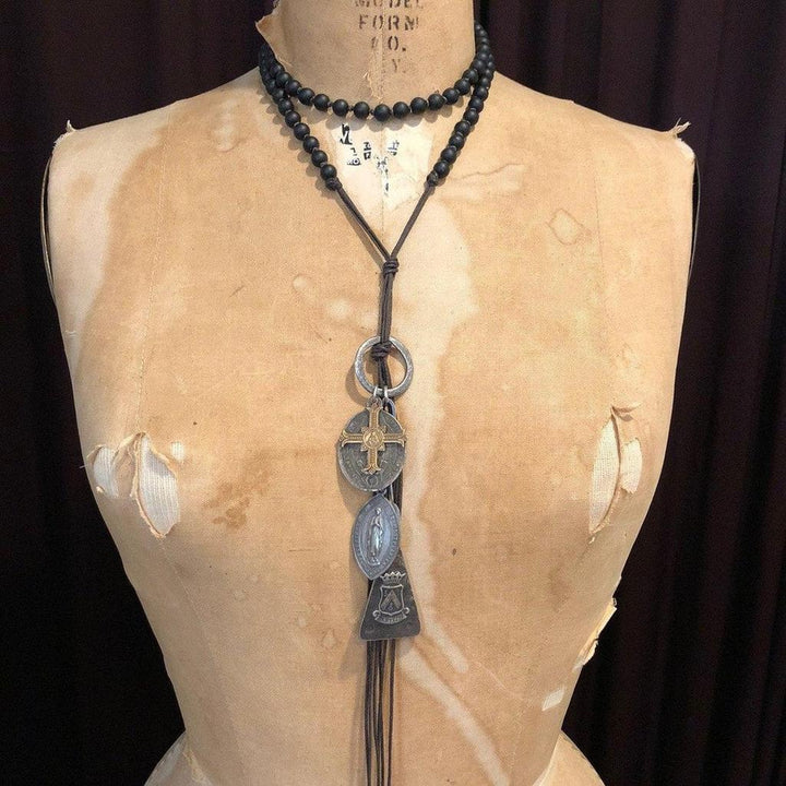 Long layered necklace with black beads and antique-style medallions.

