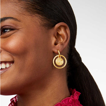 Gold double-circle earrings with textured detailing and a small gemstone accent.
