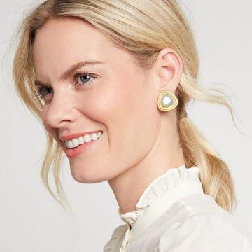 Close-up of a woman wearing gold and pearl triangle stud earrings.

