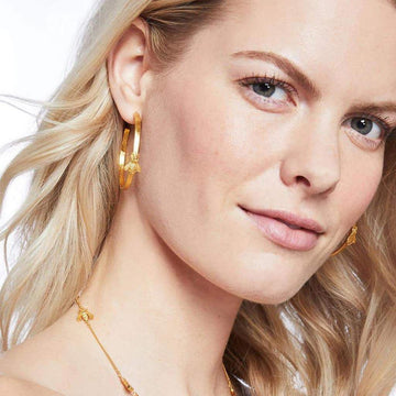 Gold bee hoop earrings on a model.
