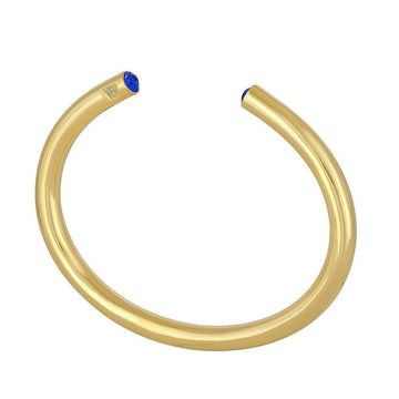 Gold bangle bracelet featuring small blue gemstones.
