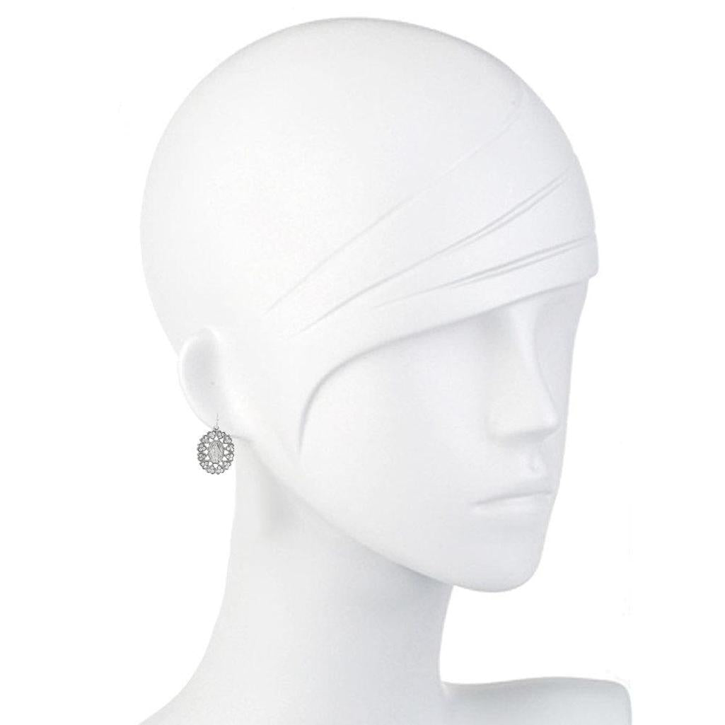 Silver drop earrings on a mannequin, featuring an ornate circular design.
