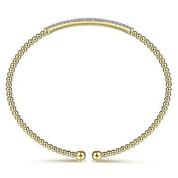 Gold beaded bangle bracelet featuring a pave diamond bar.
