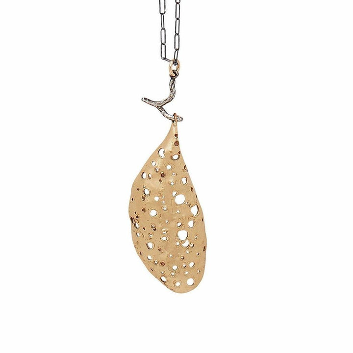 Gold Cocoon pendant necklace with oxidized silver chain and branch detail.
