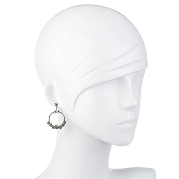Silver hoop earrings adorned with small dark stones and stars, shown on a mannequin.

