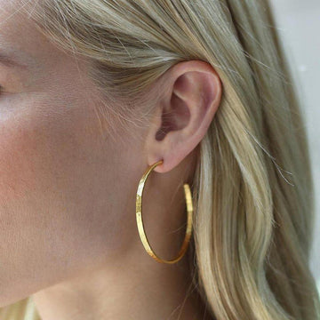 Gold hammered crescent hoop earrings worn by blonde model.
