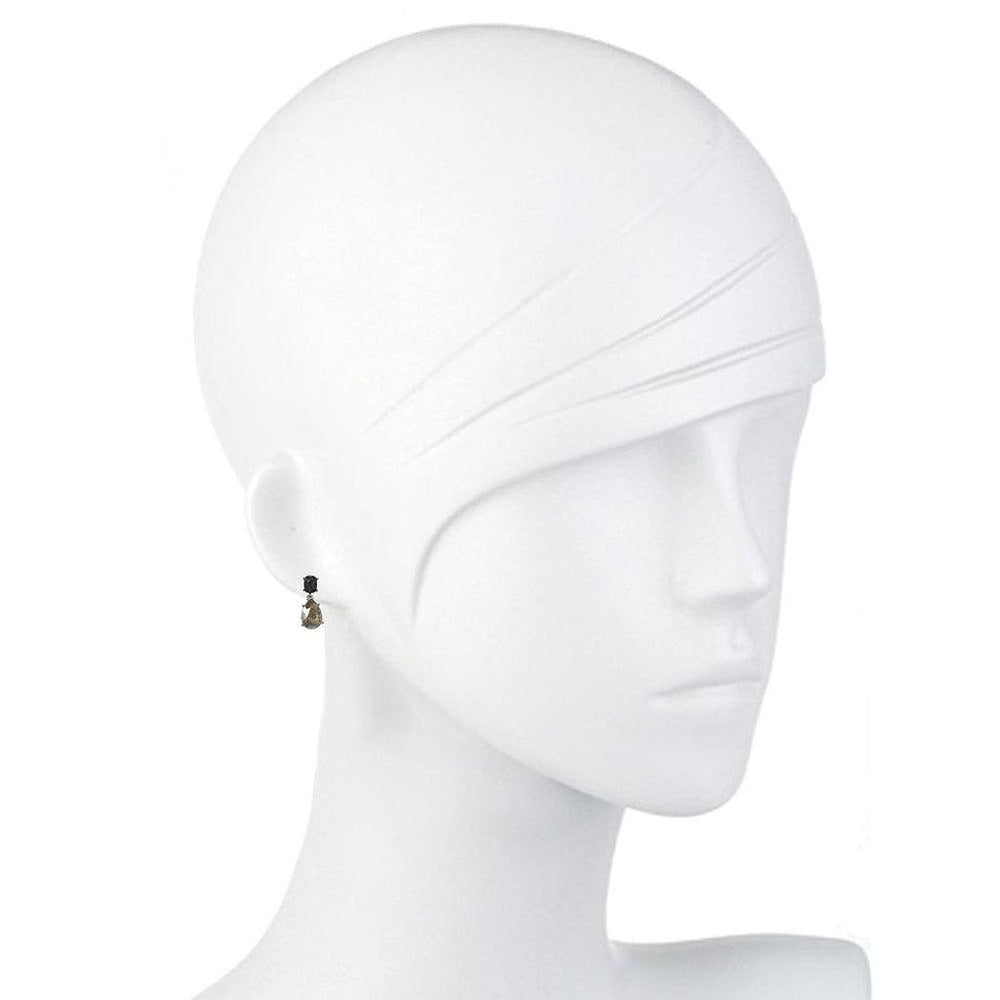 Elegant teardrop earrings displayed on a mannequin, featuring a dark stone and smaller accent.

