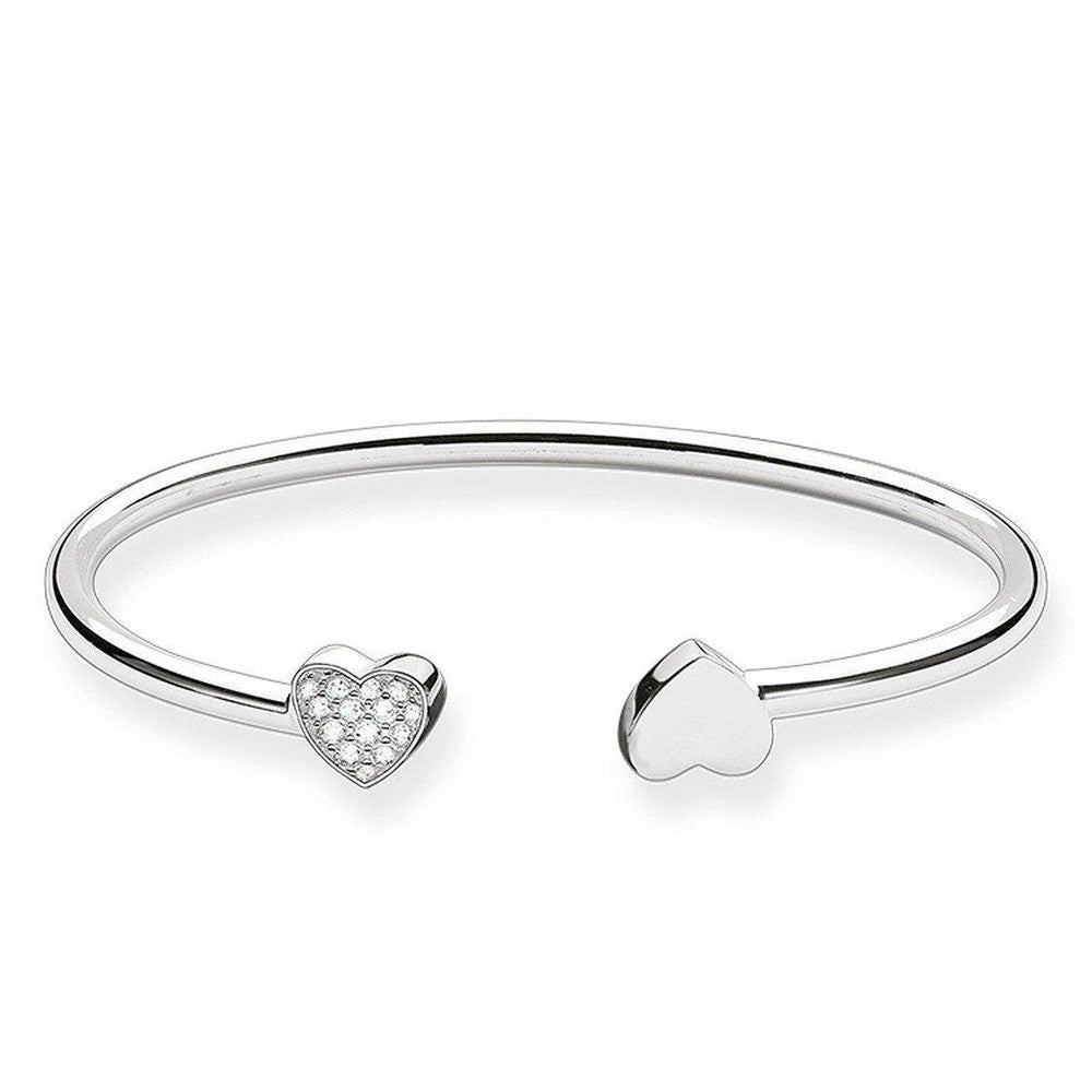 Silver cuff bracelet featuring two heart charms; one embellished with cubic zirconia.
