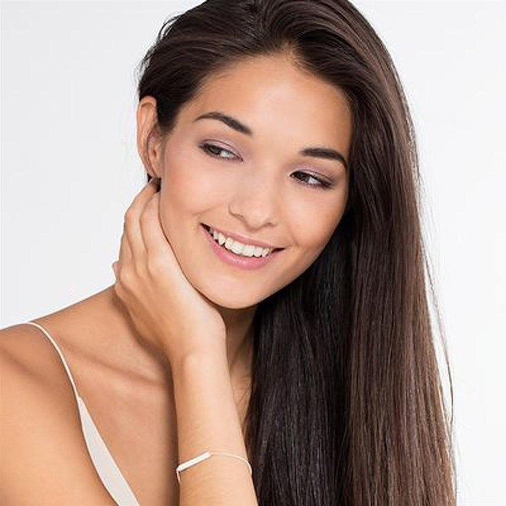 Woman wearing a delicate silver bar bracelet.
