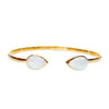 Gold cuff bracelet with two teardrop-shaped white stones.
