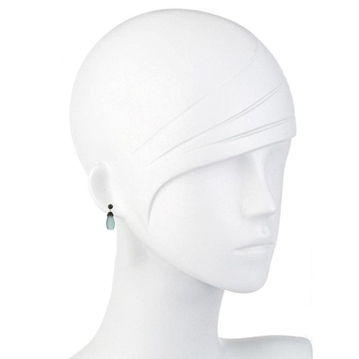 Teardrop gemstone earrings on a mannequin, showcasing light blue and dark gray stones.
