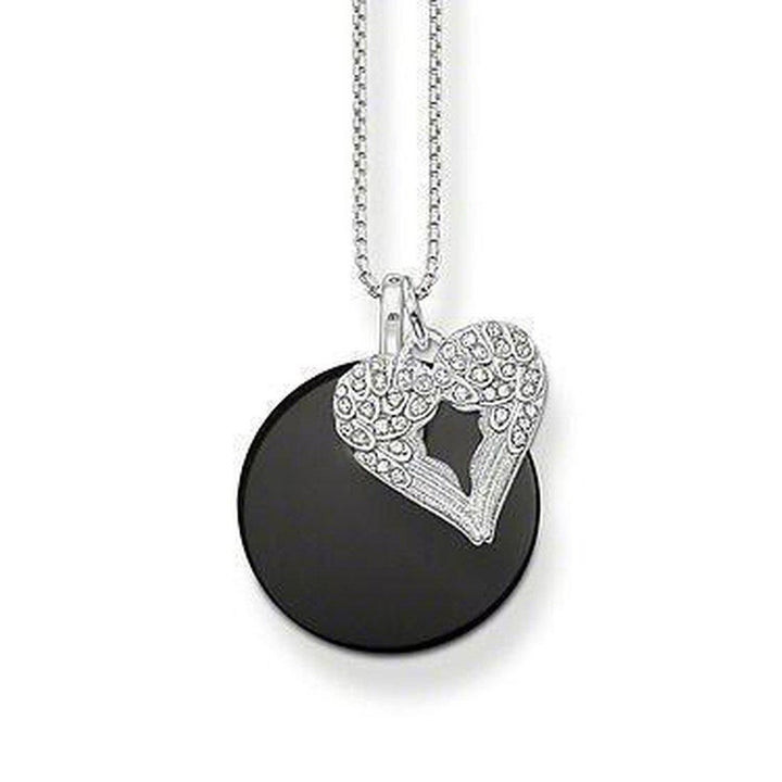 Black disc pendant necklace with a silver heart charm featuring detailed wings.
