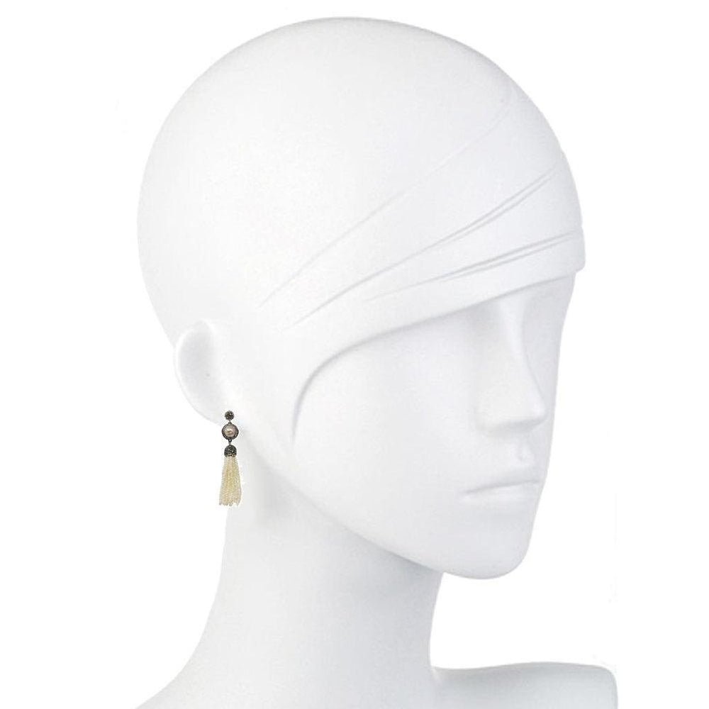 Elegant cream pearl and hematite tassel earrings on a mannequin.
