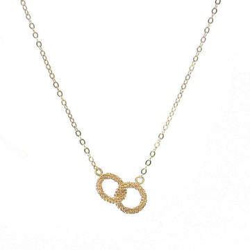 Gold infinity necklace with delicate chain and textured interlocking circles.
