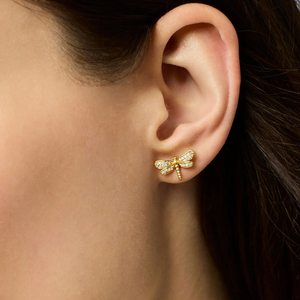 Small 24K gold-plated dragonfly stud earrings featuring delicate pave CZ crystals worn on a pierced earlobe.