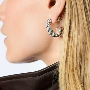 Silver-plated Ravello hoop earring with a brushed, ribbed texture worn on a pierced ear.
