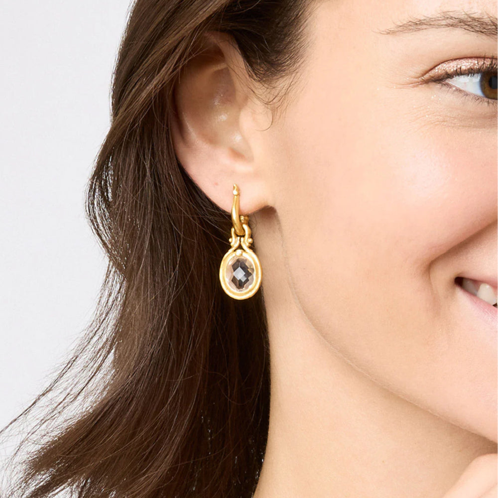 Saratoga huggie hoop earrings in 24K gold plate featuring a faceted crystal charm on a woman's ear.