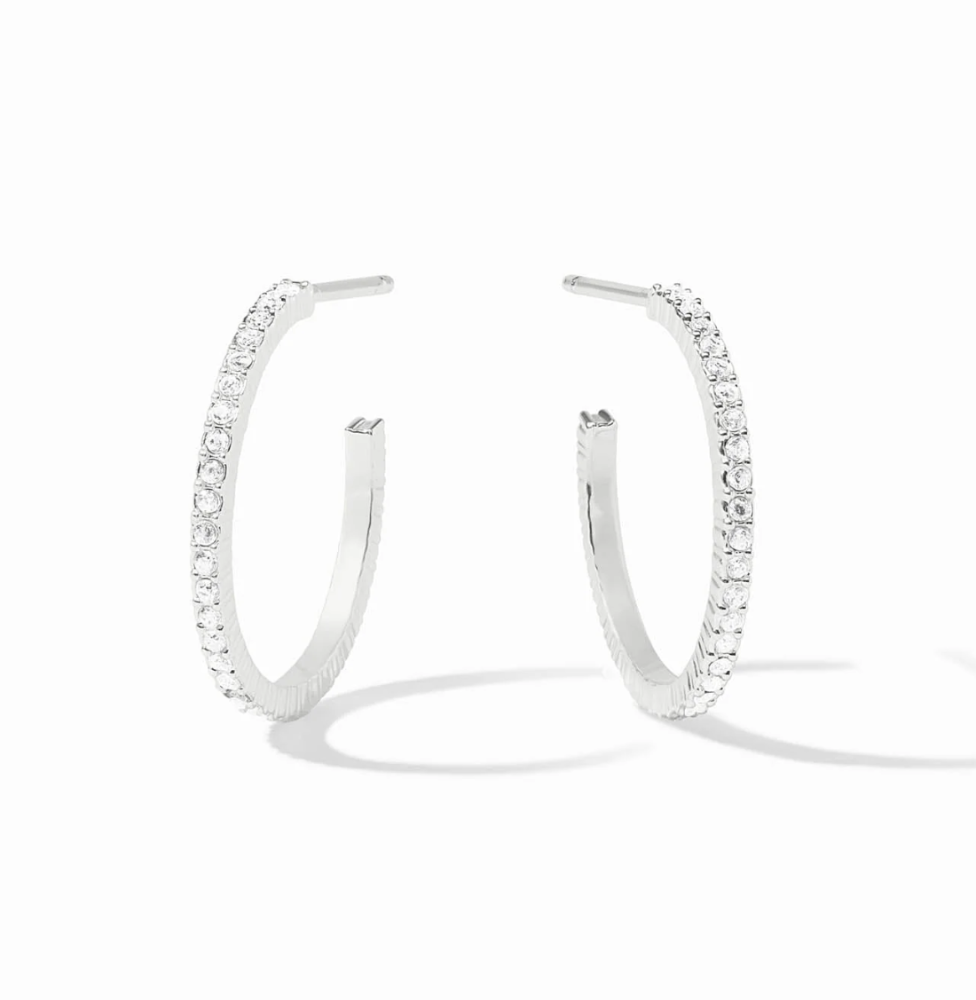 A pair of silver hoop earrings with a row of clear pavé-set stones, displayed on a clean white background with soft shadows.