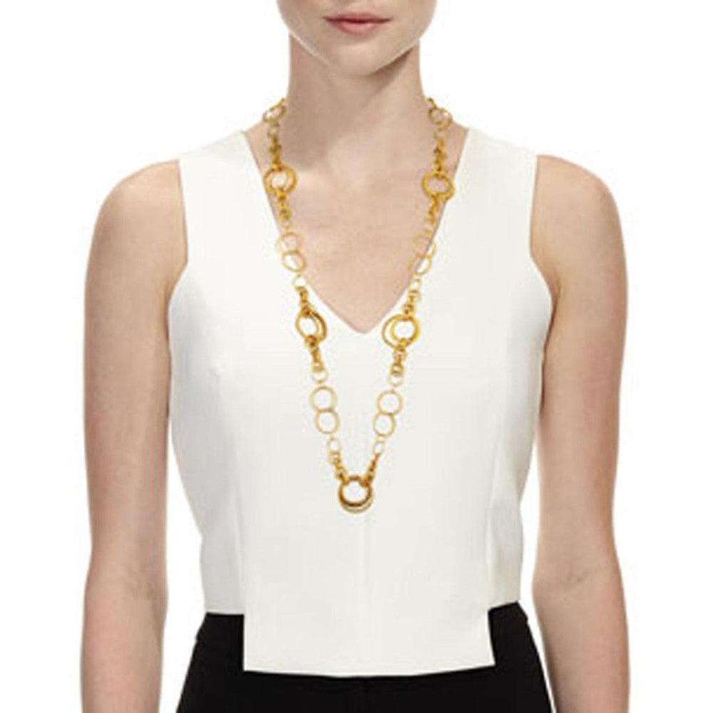 Long gold necklace with linked circle charms, shown on a model.
