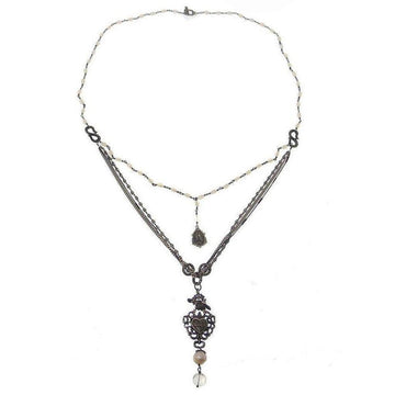 Layered necklace featuring pearl beads, metal chains, and ornate heart pendant.
