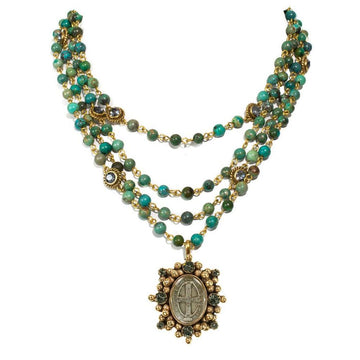 Three-strand turquoise bead necklace with gold accents and a detailed medallion pendant.
