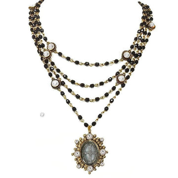 Layered black bead necklace with gold accents and a detailed antique-style pendant.
