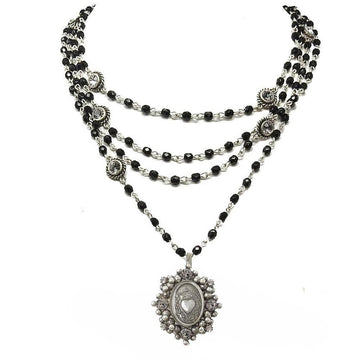 Layered black beaded necklace with silver chain and ornate heart pendant.
