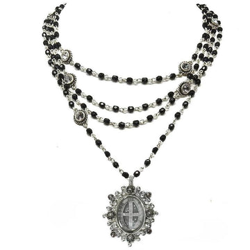 Layered black bead necklace with crystal accents and ornate pendant.
