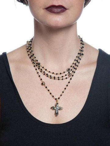 Layered black onyx and gold necklace featuring a detailed cross pendant.
