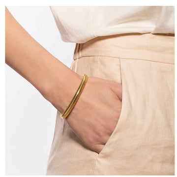 Gold open-back bracelet on a wrist, close-up view.
