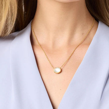 Gold chain necklace featuring a  white gemstone pendant on a lavender blouse.
