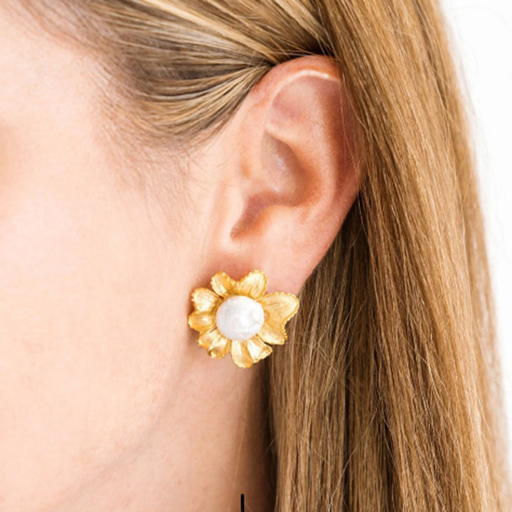 Hand-cast gold plated marigold flower stud earrings with a central white pearl, worn on an earlobe.