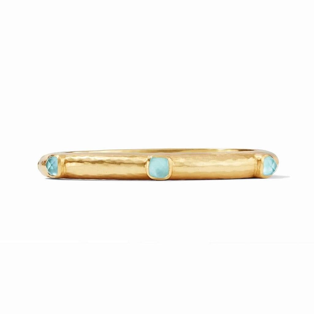 Gold hinged bangle featuring light blue gemstones.
