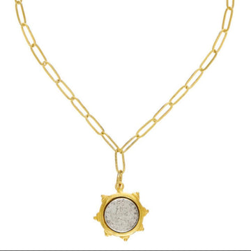 Gold chain necklace featuring a vintage silver coin pendant.
