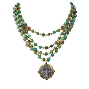 Layered turquoise and gold bead necklace with a detailed metal pendant.
