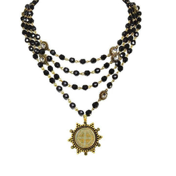 Layered black bead necklace with gold accents and a medallion pendant.
