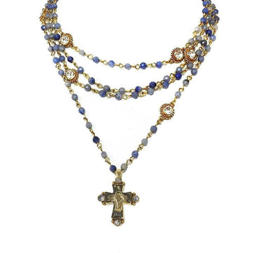 Layered blue gemstone and gold beaded necklace with a detailed cross pendant.
