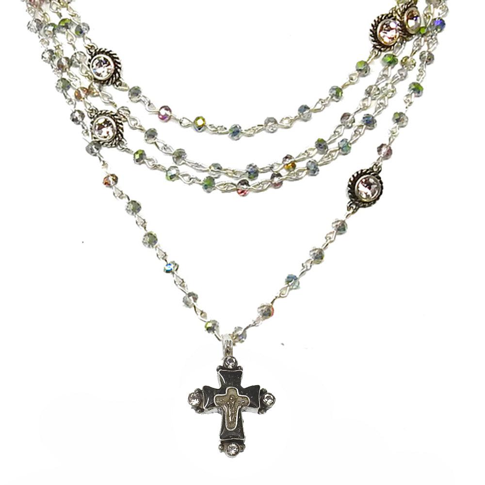 Layered silver necklace featuring a cross pendant and iridescent crystal accents.
