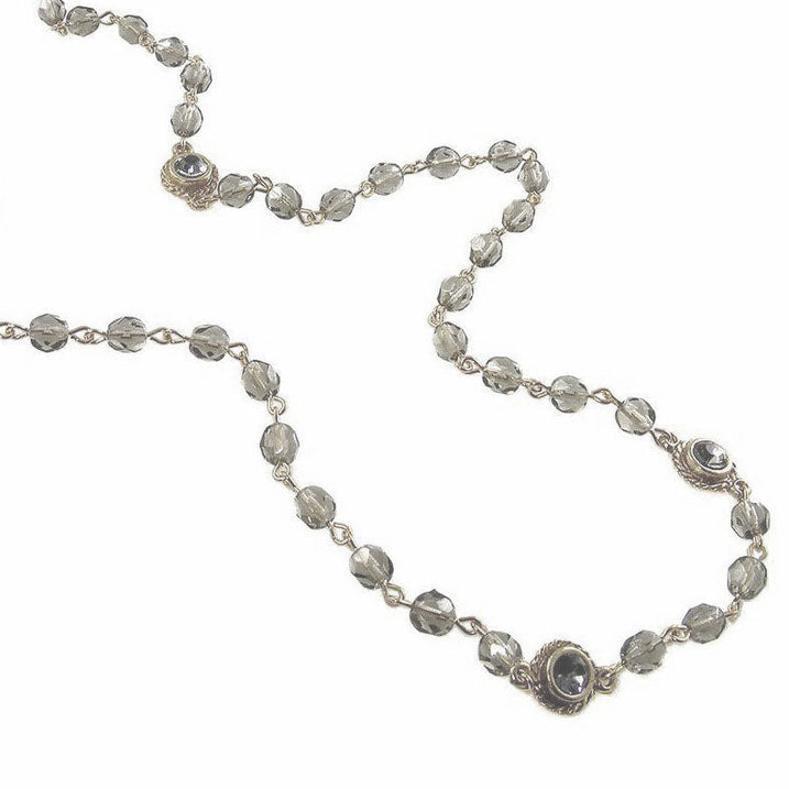 Gray glass bead necklace with gold accents, featuring faceted stones.
