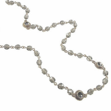 Gray glass bead necklace with gold accents, featuring faceted stones.
