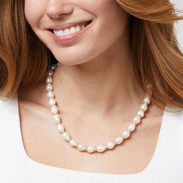 Creamy white pearl necklace with gold accents, shown on a model.

